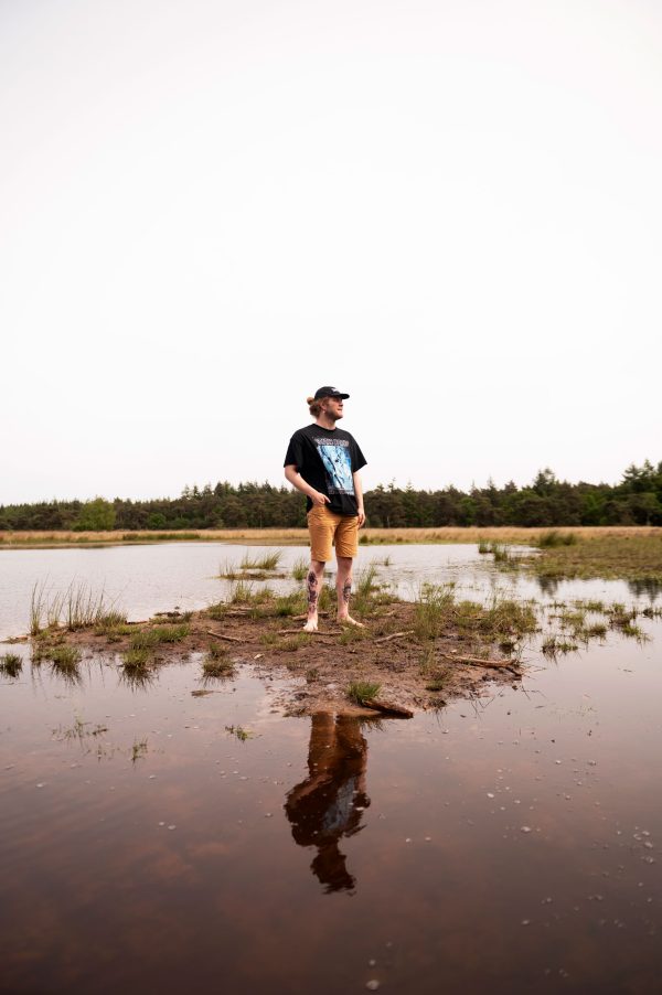 Man op blotte voeten in de natuur en water.